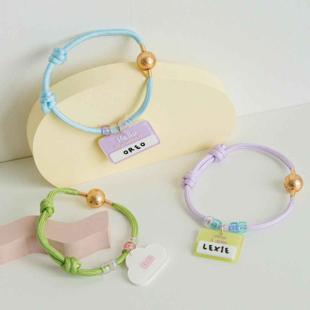 Three colorful bracelets with name tags on a light background